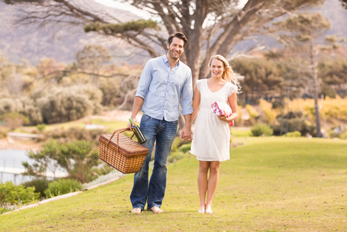 couple walking in grass with picnic basket