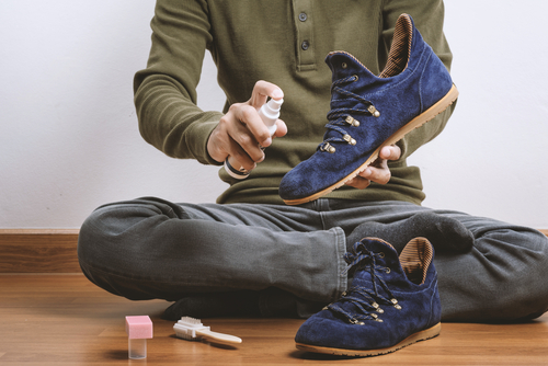 man cleaning pair of suede shoes